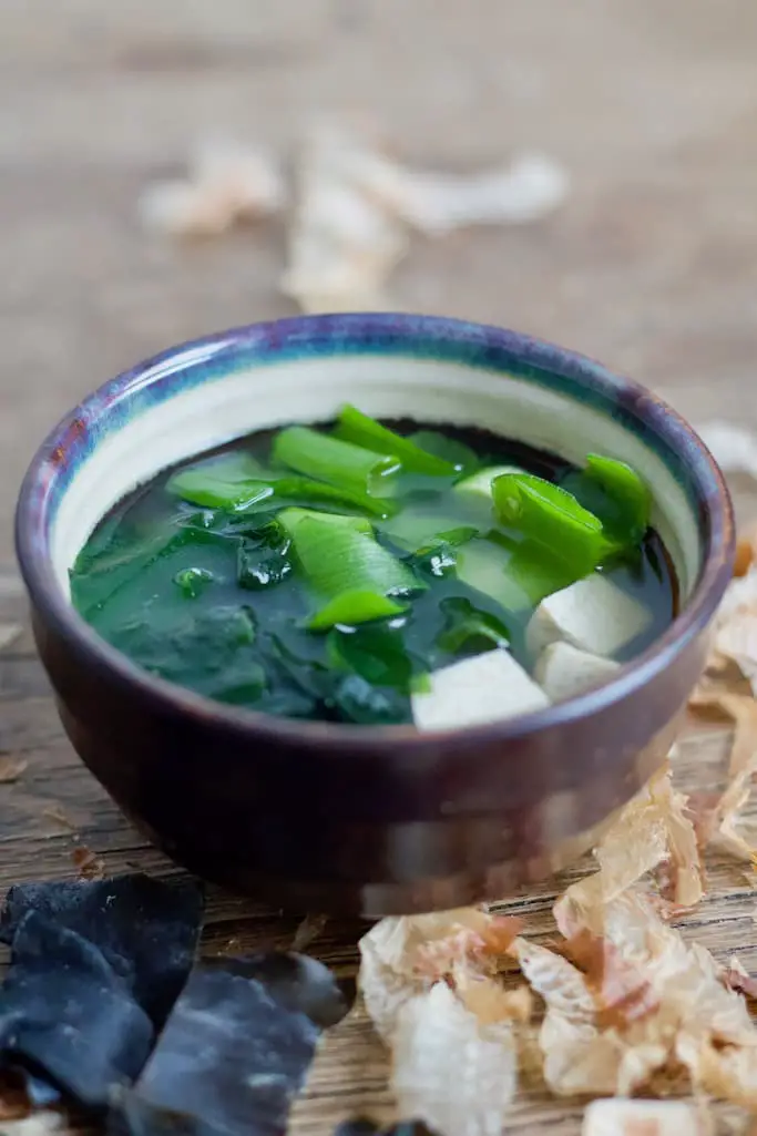 Miso Suppe mit Frühlingszwiebeln, Tofu und Algen in einer Keramikschale