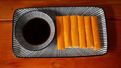 Surimi liegt zusammen mit einer Schale Sojasauce auf einem Teller