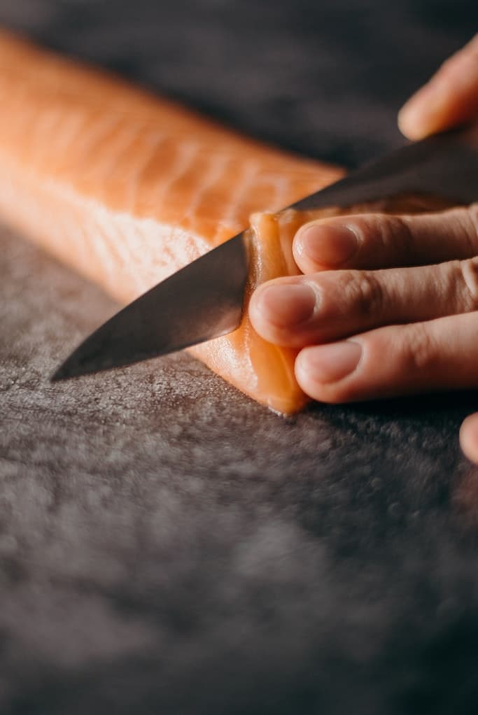 Sushi Lachs wird mit einem japanischen Messer geschnitten